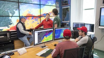 (standing l. to r.) Professor of Marine and Coastal Sciences Scott Glenn, Associate Professor of Marine and Coastal Sciences Josh Kohut, and Samuel Coakley (SEBS '18) collaborate as (sitting l. to r.) Ryan Schmidt (SEBS '22) and Research Project Assistant of the Department of Marine and Coastal Sciences Jaden Dicopoulos work in the Cool Room (Coastal Ocean Observing Leadership)
